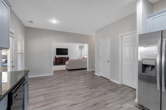 kitchen with dishwasher, light hardwood / wood-style floors, dark stone countertops, and stainless steel refrigerator with ice dispenser