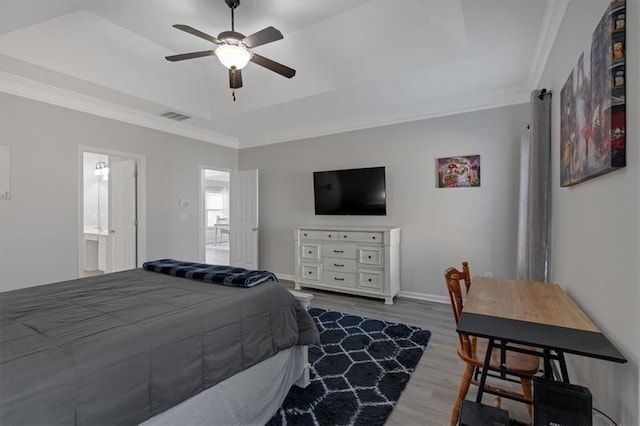 bedroom featuring a raised ceiling, ensuite bathroom, crown molding, and hardwood / wood-style floors