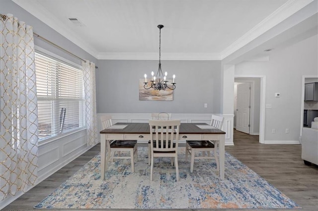 dining space with dark hardwood / wood-style flooring, ornamental molding, and an inviting chandelier