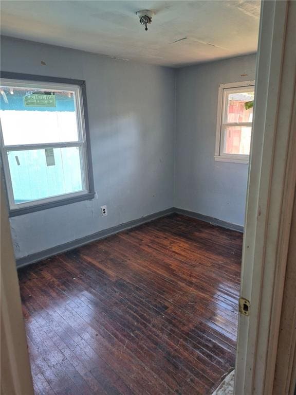 empty room featuring dark wood-style floors and baseboards