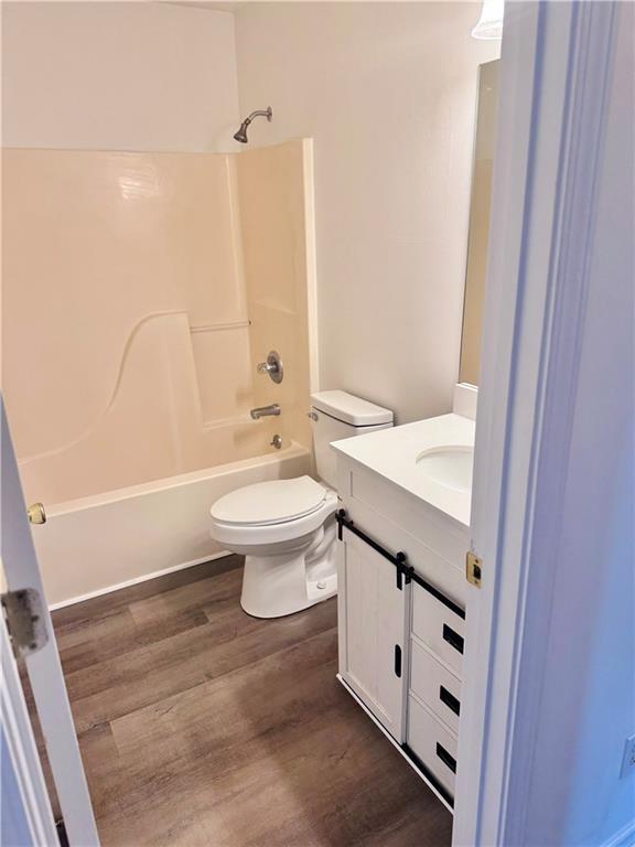 bathroom with vanity, toilet, wood finished floors, and tub / shower combination