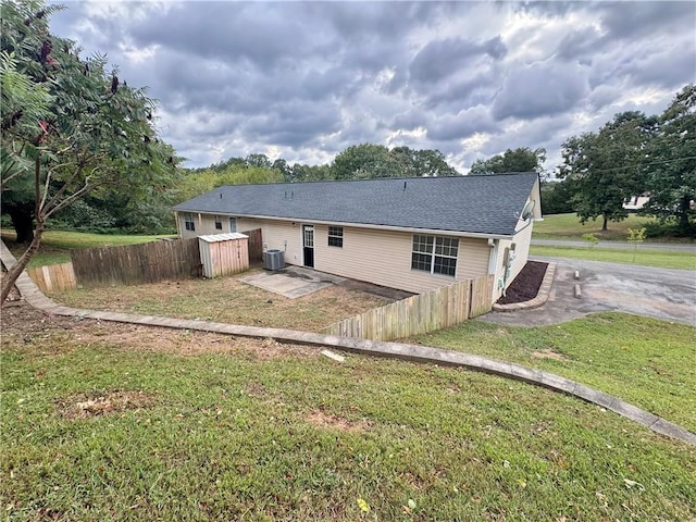 rear view of house with a patio, a lawn, central AC unit, and fence