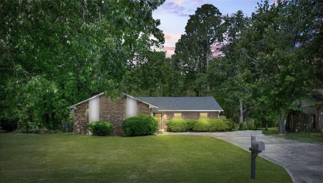 view of front of home with concrete driveway, a lawn, and stone siding