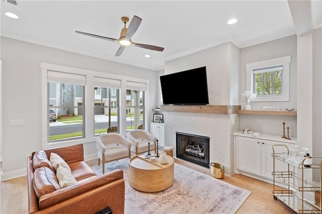 1010 Fendley St, Woodstock, GA 30188 - living area featuring a tiled fireplace, a ceiling fan, light wood finished floors, baseboards, and ornamental molding