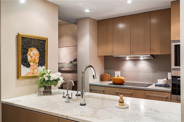 kitchen featuring sink, black electric stovetop, light stone countertops, decorative backsplash, and stainless steel oven