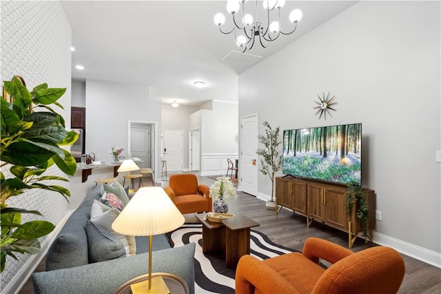 living room featuring a towering ceiling, an inviting chandelier, and dark hardwood / wood-style flooring