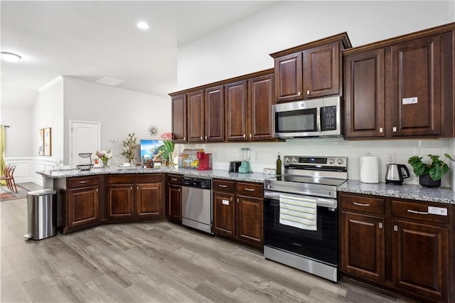 kitchen featuring light hardwood / wood-style floors, dark brown cabinets, decorative backsplash, and appliances with stainless steel finishes