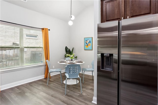 kitchen with light wood-type flooring, dark brown cabinets, stainless steel refrigerator with ice dispenser, hanging light fixtures, and lofted ceiling