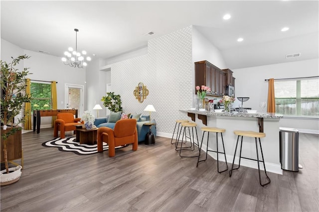 kitchen featuring hardwood / wood-style floors, light stone countertops, dark brown cabinets, and kitchen peninsula