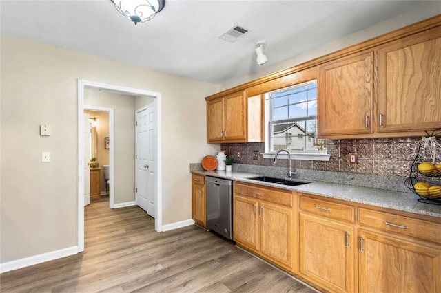 kitchen featuring light wood finished floors, tasteful backsplash, visible vents, a sink, and dishwasher