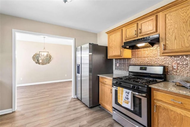 kitchen with stainless steel appliances, backsplash, light wood-style flooring, and under cabinet range hood