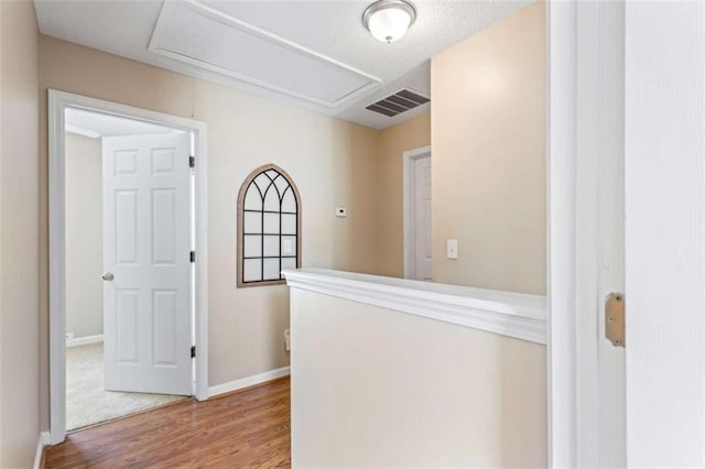 hallway featuring visible vents, baseboards, and wood finished floors