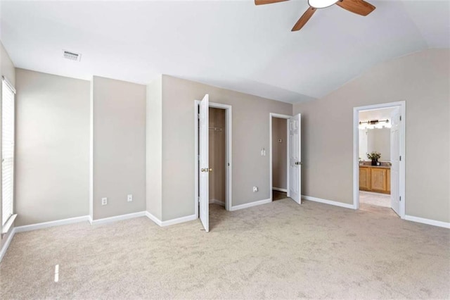 unfurnished bedroom featuring vaulted ceiling, multiple windows, carpet, and visible vents