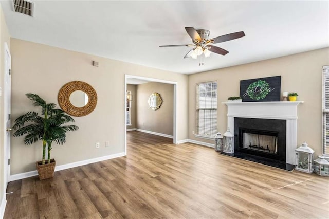 living room with a fireplace, wood finished floors, visible vents, and baseboards