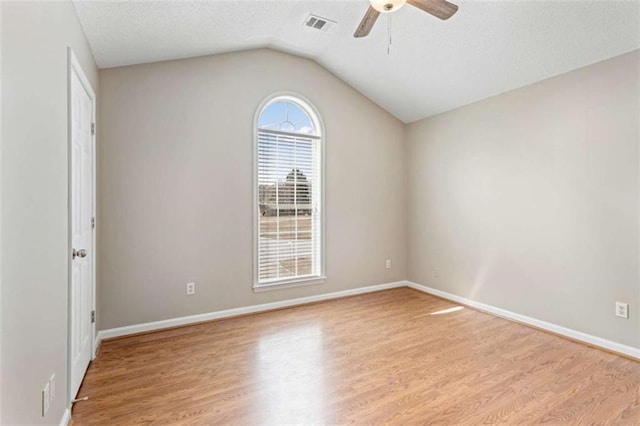 unfurnished bedroom featuring wood finished floors, baseboards, vaulted ceiling, a spacious closet, and a closet