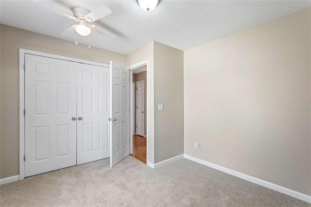 unfurnished bedroom with a textured ceiling, baseboards, a closet, and light colored carpet