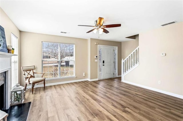 foyer featuring a fireplace, visible vents, stairway, wood finished floors, and baseboards