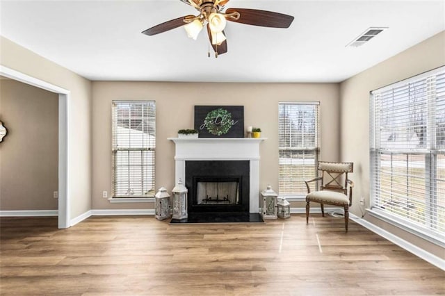 sitting room featuring a wealth of natural light, a fireplace, wood finished floors, and visible vents