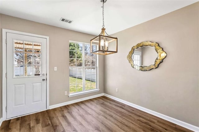 unfurnished dining area featuring baseboards, plenty of natural light, visible vents, and wood finished floors