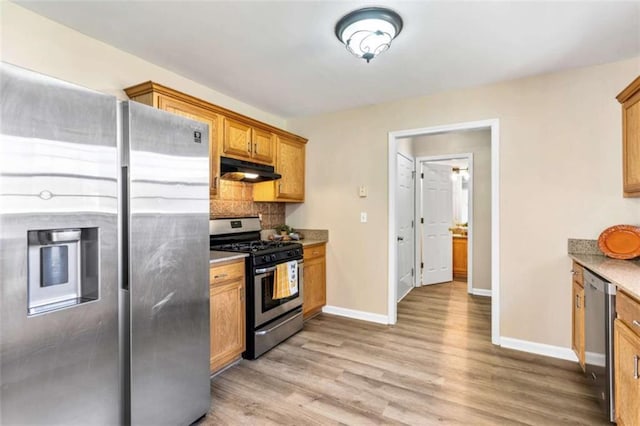 kitchen with light wood-style flooring, decorative backsplash, appliances with stainless steel finishes, under cabinet range hood, and baseboards