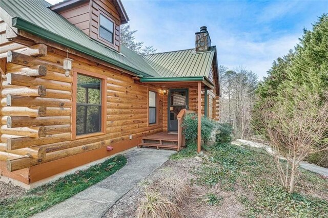 exterior space with metal roof, log exterior, and a standing seam roof