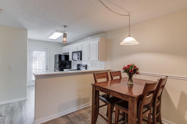 dining space with baseboards, a textured ceiling, and light wood finished floors