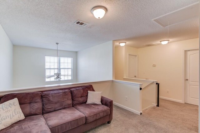 living area featuring visible vents, baseboards, attic access, light carpet, and a textured ceiling