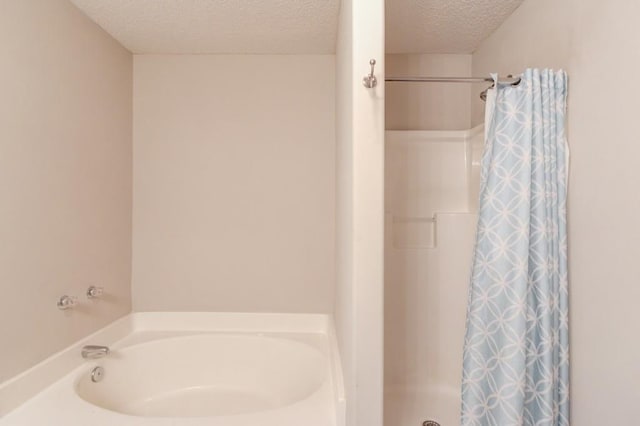 full bathroom featuring a shower stall, a textured ceiling, and a garden tub