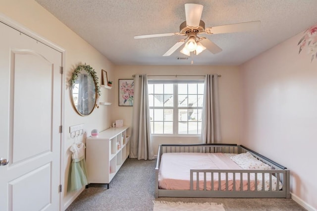 carpeted bedroom featuring visible vents, a textured ceiling, and a ceiling fan