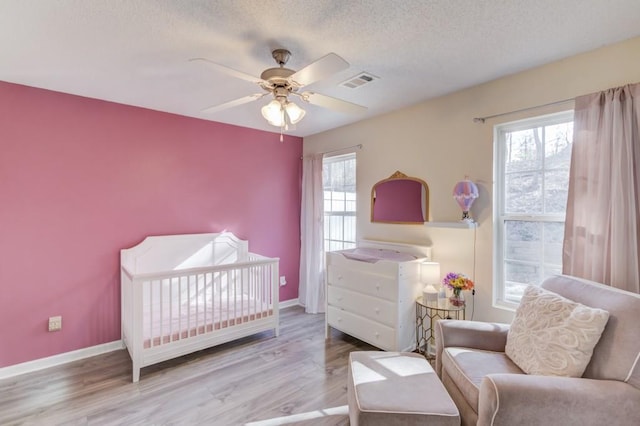 bedroom with visible vents, baseboards, a textured ceiling, and wood finished floors