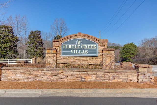 community / neighborhood sign featuring fence