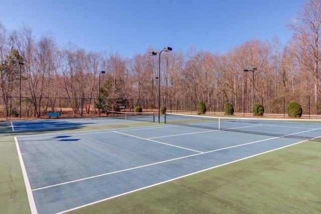 view of tennis court with community basketball court and fence