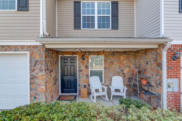 view of exterior entry featuring a garage and stone siding