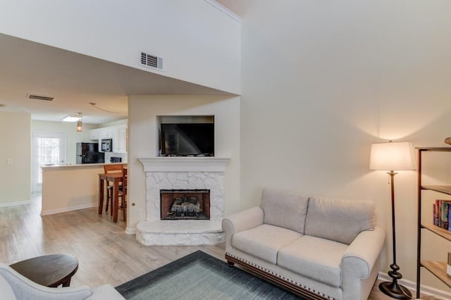 living area featuring light wood-style flooring, baseboards, and visible vents