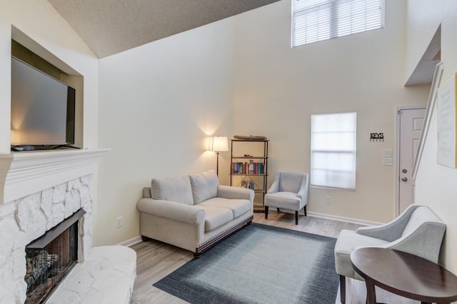 living area with a fireplace, baseboards, and wood finished floors