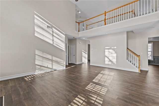 unfurnished living room with stairs, wood finished floors, and baseboards