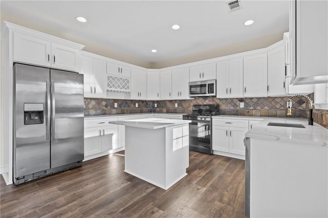 kitchen featuring visible vents, a sink, stainless steel appliances, white cabinetry, and dark wood-style flooring