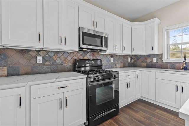 kitchen featuring gas stove, a sink, white cabinetry, stainless steel microwave, and tasteful backsplash