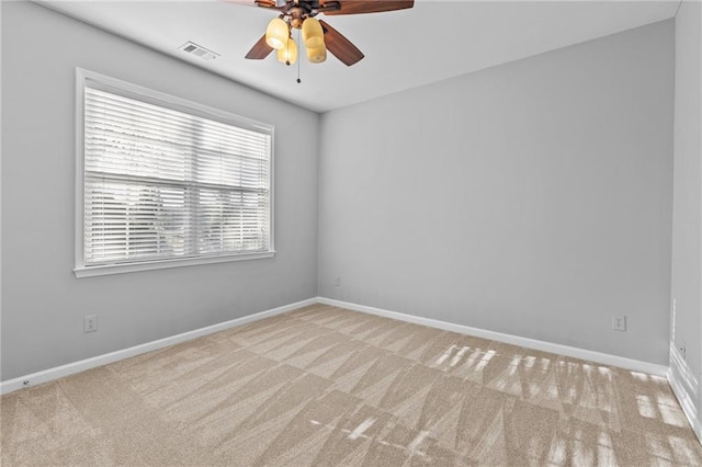 carpeted spare room with a ceiling fan, visible vents, and baseboards