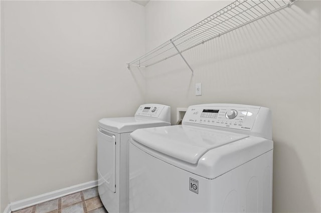 clothes washing area featuring washing machine and clothes dryer, laundry area, and baseboards