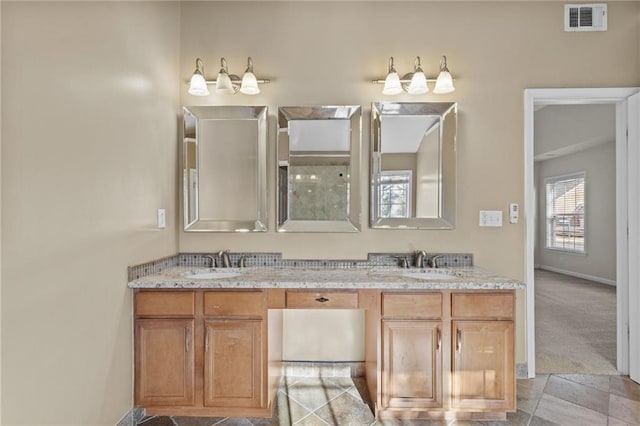 bathroom with double vanity, baseboards, visible vents, and a sink