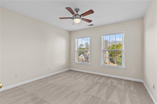 spare room with ceiling fan, baseboards, visible vents, and light carpet