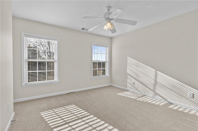 carpeted spare room featuring visible vents, baseboards, and a ceiling fan