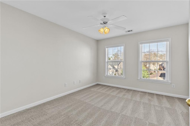 empty room with a ceiling fan, light colored carpet, visible vents, and baseboards