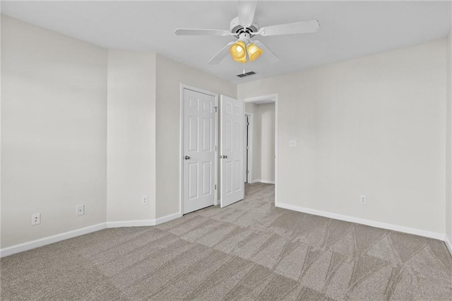 carpeted empty room featuring visible vents, a ceiling fan, and baseboards