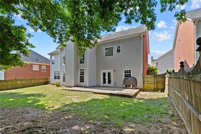 back of house featuring a patio area, a lawn, french doors, and a fenced backyard