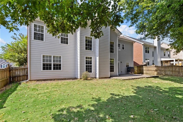 rear view of property with a patio, a lawn, and a fenced backyard