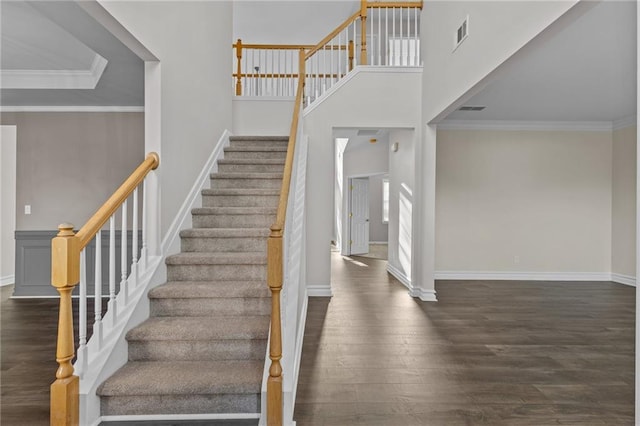 stairway featuring visible vents, wood finished floors, baseboards, and ornamental molding