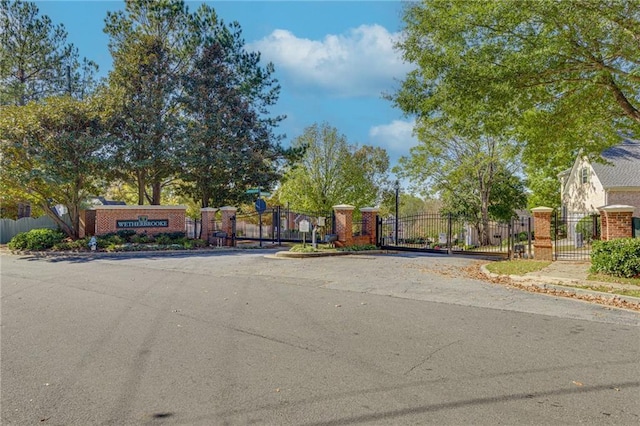 view of road featuring curbs, a gated entry, sidewalks, and a gate