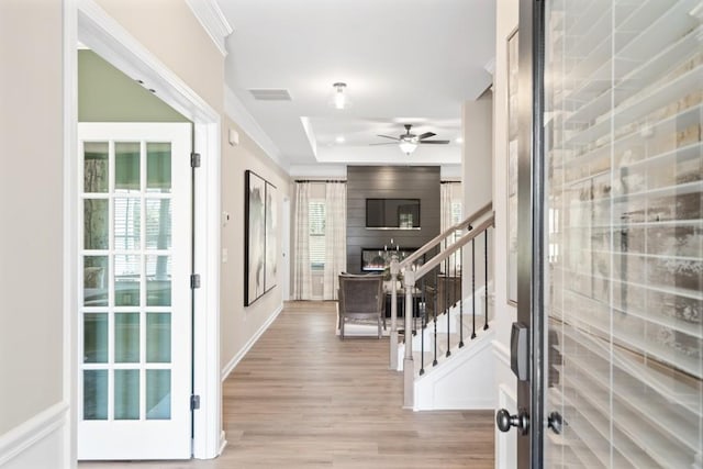 entrance foyer featuring crown molding, stairway, visible vents, and light wood-style floors